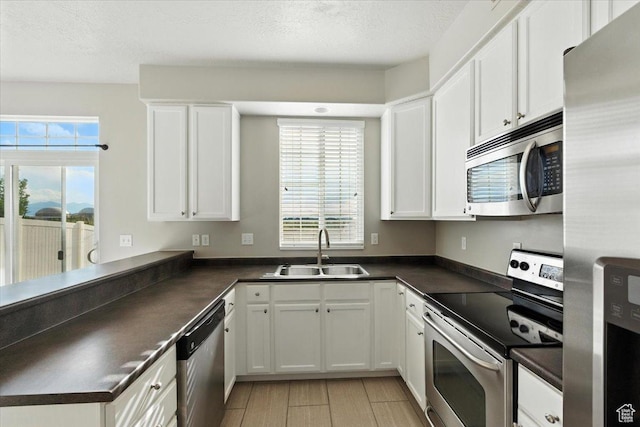 729 N Buckingham Dr W, North Salt Lake, UT 84054 - kitchen with appliances with stainless steel finishes, dark countertops, healthy amount of natural light, a peninsula, and a textured ceiling