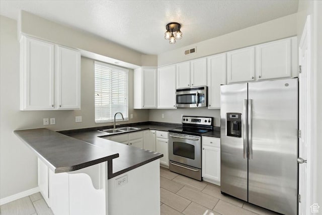 729 N Buckingham Dr W, North Salt Lake, UT 84054 - kitchen with stainless steel appliances, dark countertops, a peninsula, white cabinets, and a textured ceiling