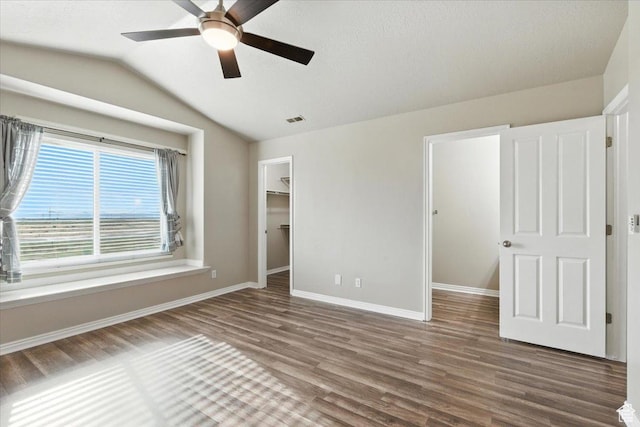 729 N Buckingham Dr W, North Salt Lake, UT 84054 - unfurnished bedroom featuring wood finished floors, a walk in closet, vaulted ceiling, and ceiling fan