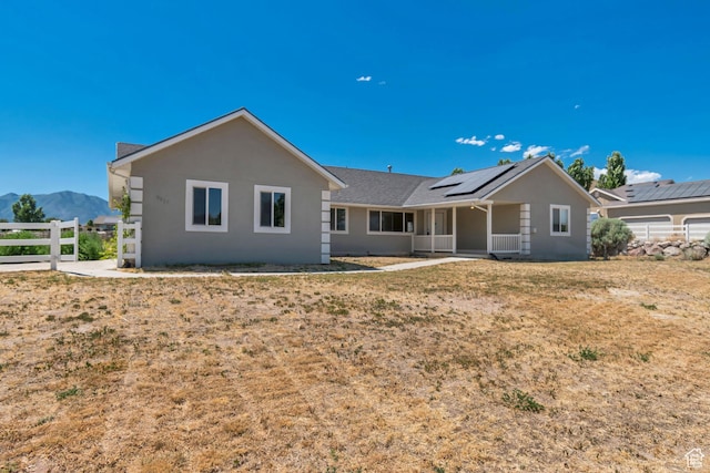 9517 N Shiloh Way E, Eagle Mountain, UT 84005 - back of property with solar panels, a mountain view, stucco siding, and a porch