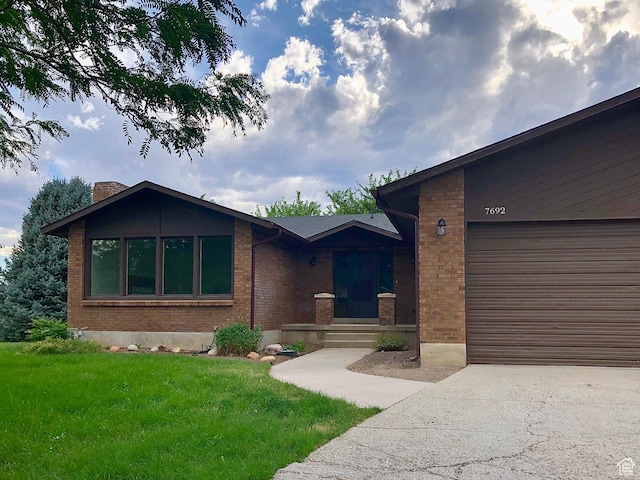 7692 S Chad St, Midvale, UT 84047 - view of front of home with brick siding, a front lawn, driveway, an attached garage, and a chimney
