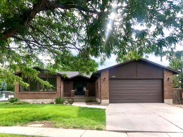 7692 S Chad St, Midvale, UT 84047 - view of front of house featuring driveway, an attached garage, brick siding, and a front lawn