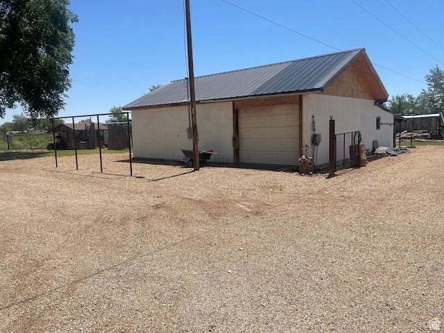 5518 E 500 N, Fort Duchesne, UT 84026 - view of property exterior featuring a garage, an outbuilding, a metal roof, driveway, and stucco siding