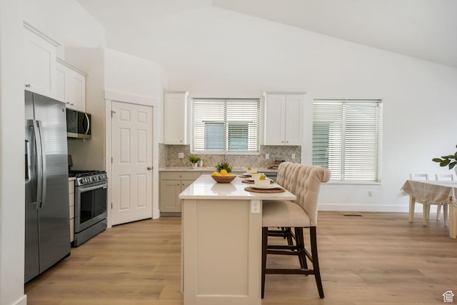 749 E 1600 S, Orem, UT 84097 - kitchen with appliances with stainless steel finishes, lofted ceiling, a breakfast bar area, decorative backsplash, and light wood-style floors