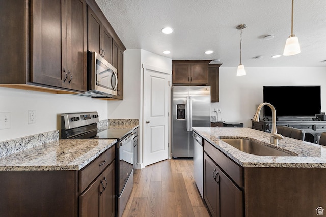 1152 S 800 W, Spanish Fork, UT 84660 - kitchen featuring stainless steel appliances, dark brown cabinetry, light wood finished floors, an island with sink, and a textured ceiling