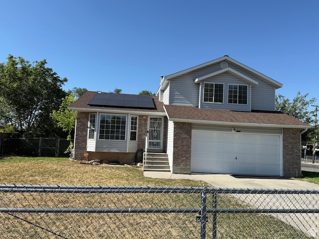 6410 W Martin Way S, West Valley City, UT 84128 - view of front of property with an attached garage, solar panels, driveway, and brick siding