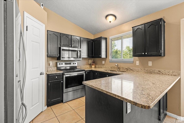 6410 W Martin Way S, West Valley City, UT 84128 - kitchen featuring stainless steel appliances, a peninsula, lofted ceiling, light tile patterned flooring, and dark cabinetry