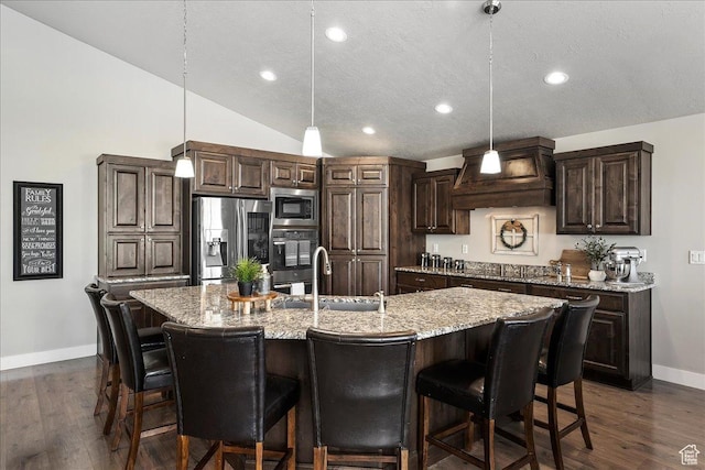 1949 N 2350 W Unit 203, Clinton, UT 84015 - kitchen with appliances with stainless steel finishes, dark brown cabinets, a kitchen breakfast bar, light stone countertops, and a center island with sink