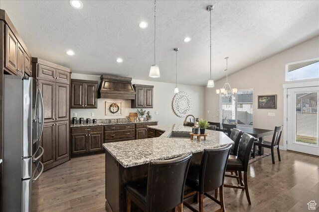 1949 N 2350 W Unit 203, Clinton, UT 84015 - kitchen featuring stainless steel fridge, custom exhaust hood, vaulted ceiling, wood finished floors, and a textured ceiling
