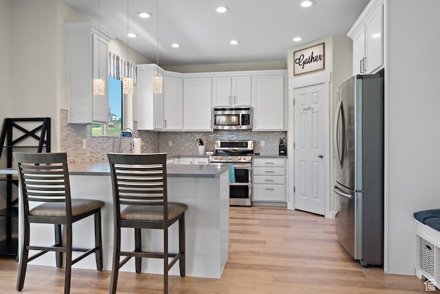 8791 N Suffolk Ln, Eagle Mountain, UT 84005 - kitchen featuring appliances with stainless steel finishes, a peninsula, light wood finished floors, white cabinets, and recessed lighting