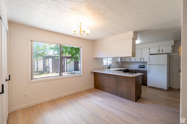 481 W Oak Crest Dr, Monticello, UT 84535 - kitchen featuring white appliances, a peninsula, a chandelier, light wood-style floors, and a textured ceiling
