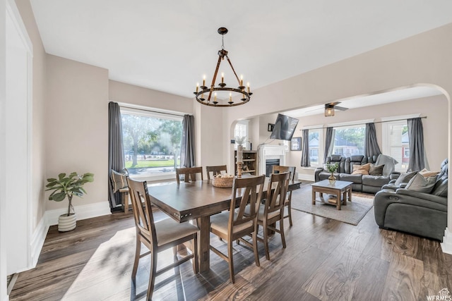 554 17th St, Ogden, UT 84404 - dining area featuring arched walkways, dark wood-style flooring, a fireplace, a chandelier, and a ceiling fan