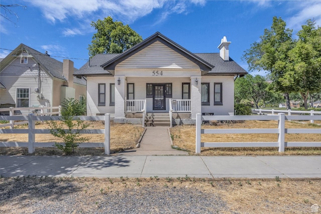 554 17th St, Ogden, UT 84404 - view of front of home featuring a porch, a fenced front yard, brick siding, a chimney, and roof with shingles