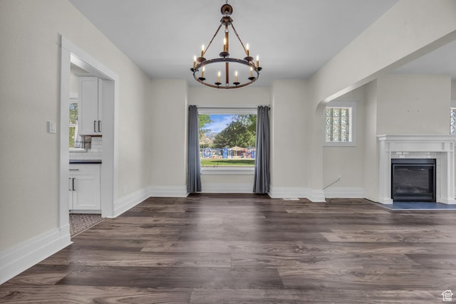 554 17th St, Ogden, UT 84404 - unfurnished dining area with healthy amount of natural light, a chandelier, a glass covered fireplace, and dark wood-style flooring