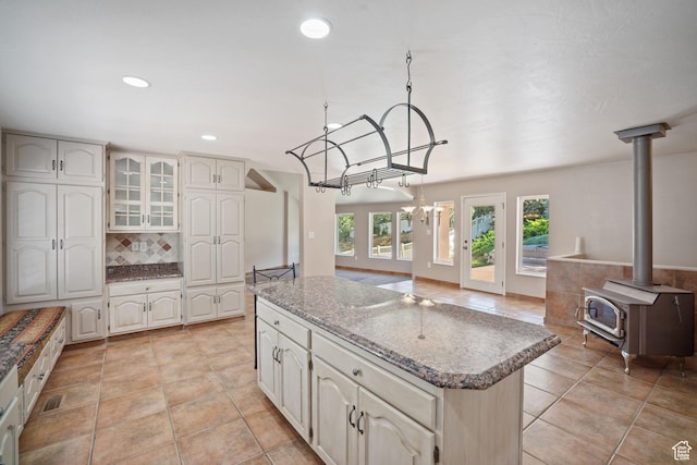 967 E Eaglewood Dr, North Salt Lake, UT 84054 - kitchen featuring a kitchen island, tasteful backsplash, recessed lighting, light tile patterned floors, and a wood stove