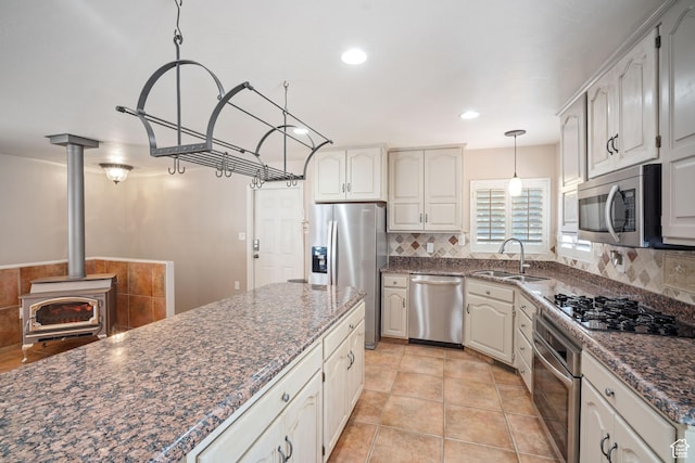 967 E Eaglewood Dr, North Salt Lake, UT 84054 - kitchen featuring appliances with stainless steel finishes, backsplash, decorative light fixtures, dark stone countertops, and a wood stove