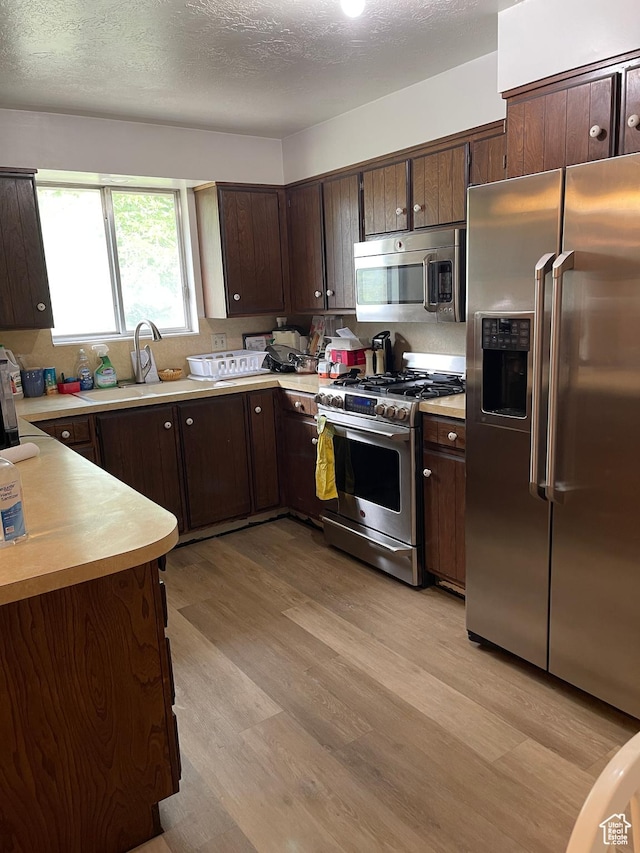 1692 W 300 N, West Point, UT 84015 - kitchen with stainless steel appliances, light countertops, dark brown cabinetry, light wood finished floors, and a textured ceiling