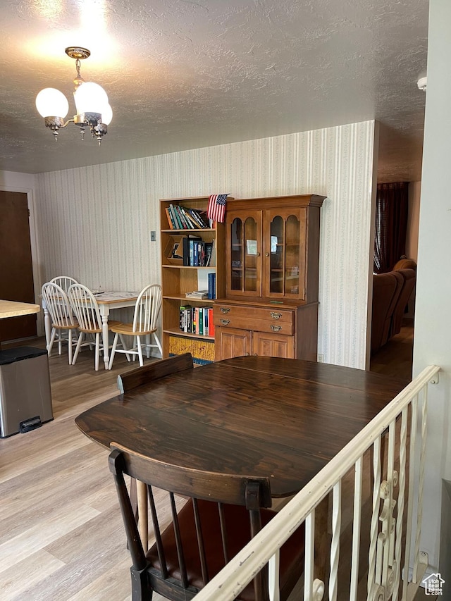1692 W 300 N, West Point, UT 84015 - dining space featuring wallpapered walls, light wood-type flooring, a chandelier, and a textured ceiling