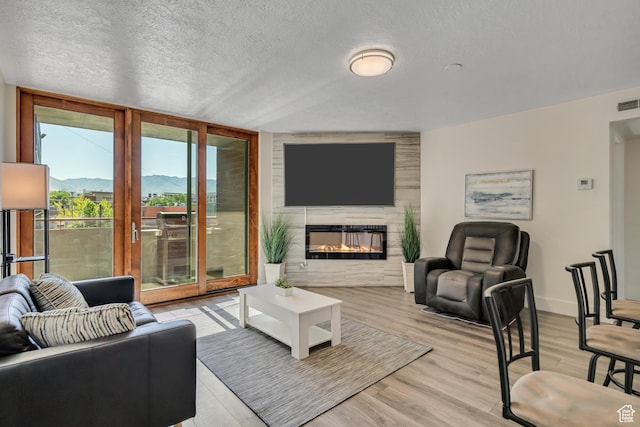 230 E Broadway Unit 401, Salt Lake City, UT 84111 - living room with light wood-style floors, a glass covered fireplace, a textured ceiling, and floor to ceiling windows