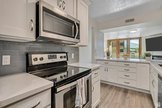 230 E Broadway Unit 401, Salt Lake City, UT 84111 - kitchen with appliances with stainless steel finishes, decorative backsplash, light countertops, light wood-style floors, and white cabinets