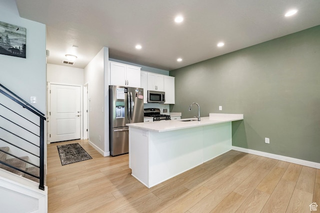 3230 W 3855 S, West Haven, UT 84401 - kitchen featuring appliances with stainless steel finishes, a peninsula, light wood finished floors, white cabinetry, and light countertops