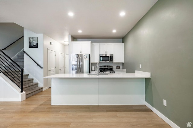 3230 W 3855 S, West Haven, UT 84401 - kitchen with stainless steel appliances, a peninsula, white cabinets, light wood-style flooring, and light countertops