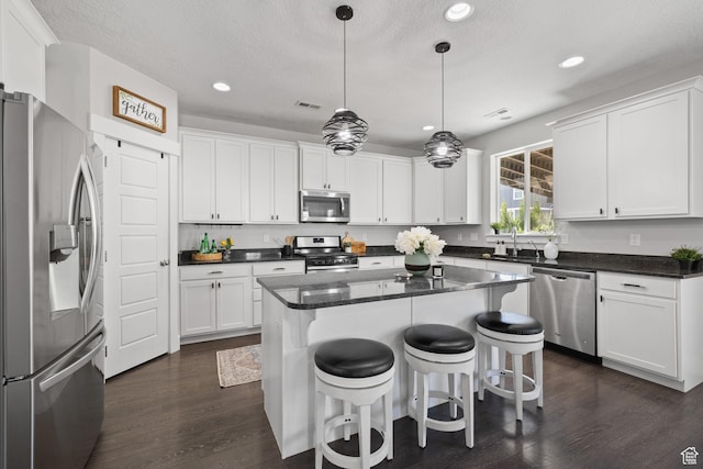 6523 W Bridge Maple Ln S, West Jordan, UT 84081 - kitchen with appliances with stainless steel finishes, dark wood-type flooring, recessed lighting, white cabinetry, and a center island