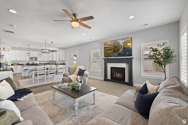 6523 W Bridge Maple Ln S, West Jordan, UT 84081 - living room featuring ceiling fan, recessed lighting, a glass covered fireplace, light carpet, and a textured ceiling