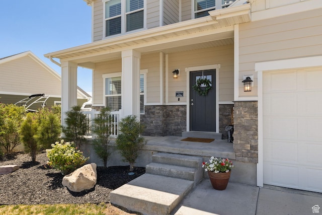 6523 W Bridge Maple Ln S, West Jordan, UT 84081 - view of exterior entry with a garage, covered porch, and stone siding