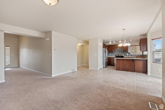 2794 W Harker Ridge Cv, Salt Lake City, UT 84129 - kitchen featuring open floor plan, stainless steel appliances, a chandelier, light colored carpet, and a textured ceiling