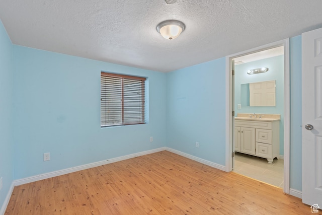 2794 W Harker Ridge Cv, Salt Lake City, UT 84129 - unfurnished bedroom featuring light wood-style flooring, a textured ceiling, and connected bathroom