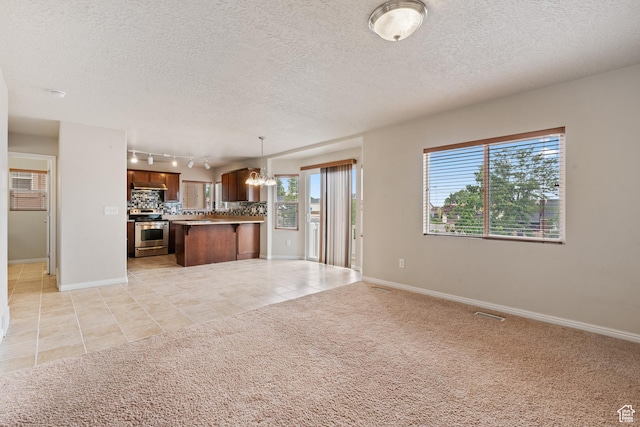2794 W Harker Ridge Cv, Salt Lake City, UT 84129 - kitchen featuring stainless steel range with electric stovetop, open floor plan, a chandelier, light tile patterned floors, and rail lighting