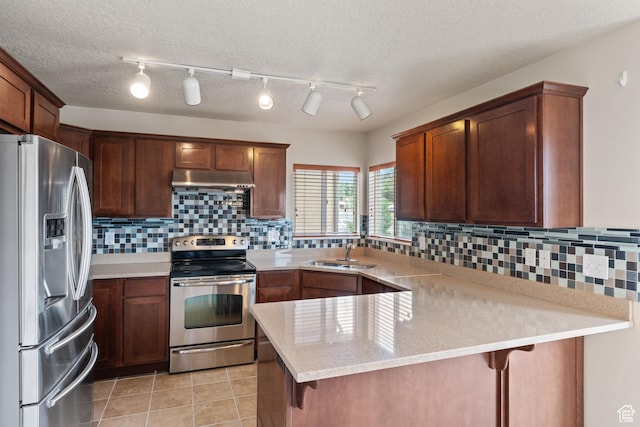 2794 W Harker Ridge Cv, Salt Lake City, UT 84129 - kitchen featuring appliances with stainless steel finishes, a peninsula, under cabinet range hood, decorative backsplash, and a breakfast bar