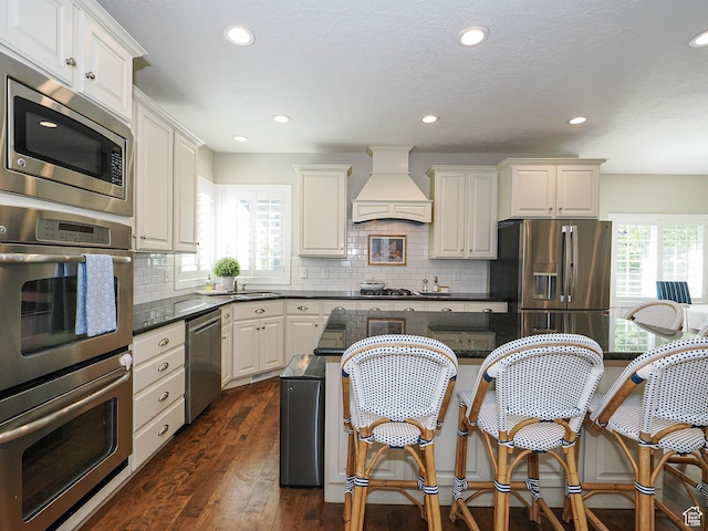 618 E Beaumont Way S, Draper, UT 84020 - kitchen featuring custom range hood, stainless steel appliances, a breakfast bar, dark wood finished floors, and decorative backsplash