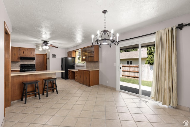 1657 E 1500 N, Logan, UT 84341 - kitchen featuring freestanding refrigerator, range, a peninsula, under cabinet range hood, and brown cabinets