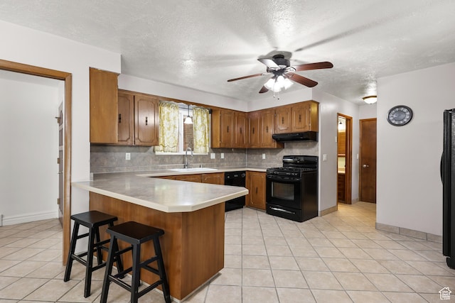 1657 E 1500 N, Logan, UT 84341 - kitchen with black appliances, under cabinet range hood, a peninsula, brown cabinets, and ceiling fan