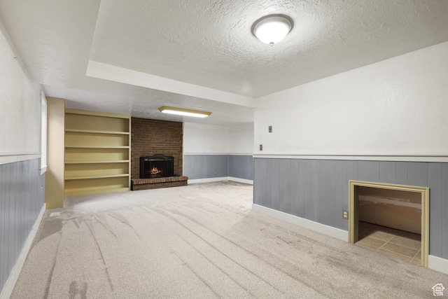 1657 E 1500 N, Logan, UT 84341 - unfurnished living room with a brick fireplace, a textured ceiling, light colored carpet, built in shelves, and a wainscoted wall