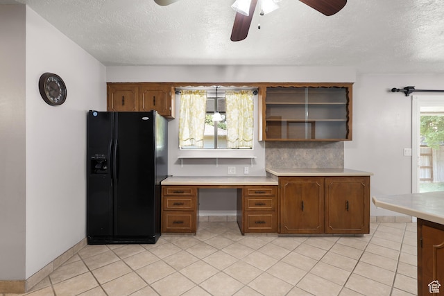 1657 E 1500 N, Logan, UT 84341 - kitchen with black fridge, ceiling fan, light countertops, a textured ceiling, and brown cabinetry
