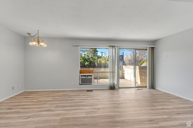 1050 Healy St Unit 1, Ogden, UT 84403 - empty room with a wall mounted air conditioner, light wood finished floors, and a chandelier