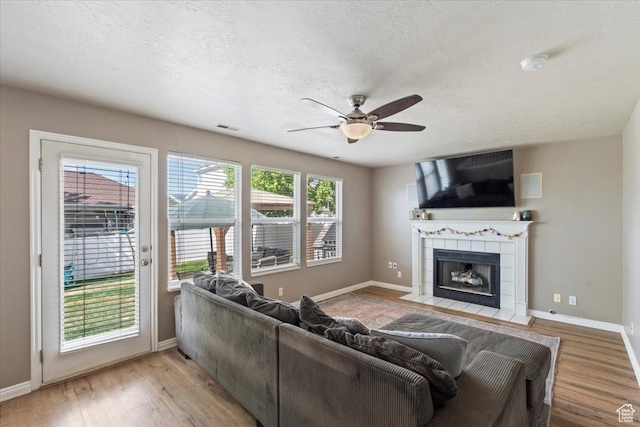 573 E Compass Cir S, North Salt Lake, UT 84054 - living area featuring a ceiling fan, a tiled fireplace, light wood-style flooring, and a textured ceiling