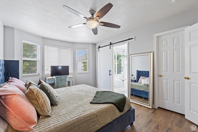 573 E Compass Cir S, North Salt Lake, UT 84054 - bedroom featuring a barn door, multiple windows, wood finished floors, a textured ceiling, and ceiling fan
