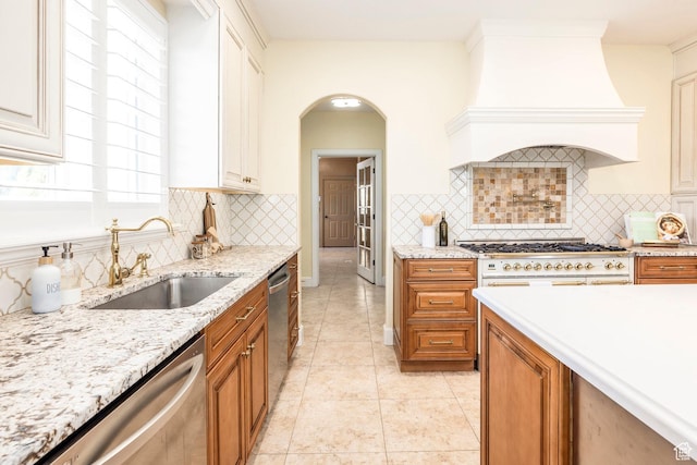 897 W Pfeifferhorn Dr, Alpine, UT 84004 - kitchen featuring dishwasher, brown cabinetry, custom range hood, light stone countertops, and decorative backsplash