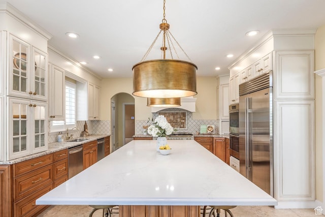897 W Pfeifferhorn Dr, Alpine, UT 84004 - kitchen featuring stainless steel appliances, a breakfast bar area, brown cabinetry, arched walkways, and backsplash
