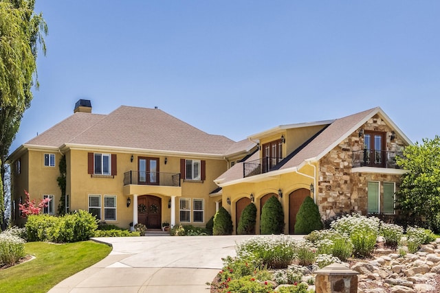 897 W Pfeifferhorn Dr, Alpine, UT 84004 - view of front of house with a balcony, french doors, driveway, stone siding, and stucco siding