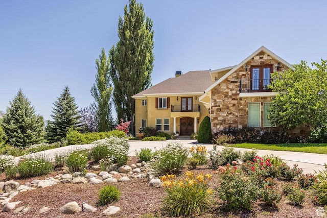 897 W Pfeifferhorn Dr, Alpine, UT 84004 - view of front of house with french doors, stone siding, a balcony, stucco siding, and a chimney