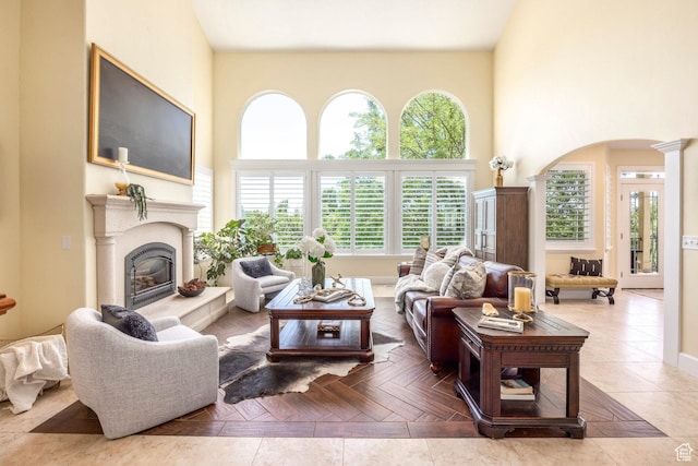 897 W Pfeifferhorn Dr, Alpine, UT 84004 - living room featuring arched walkways, a glass covered fireplace, a towering ceiling, and decorative columns