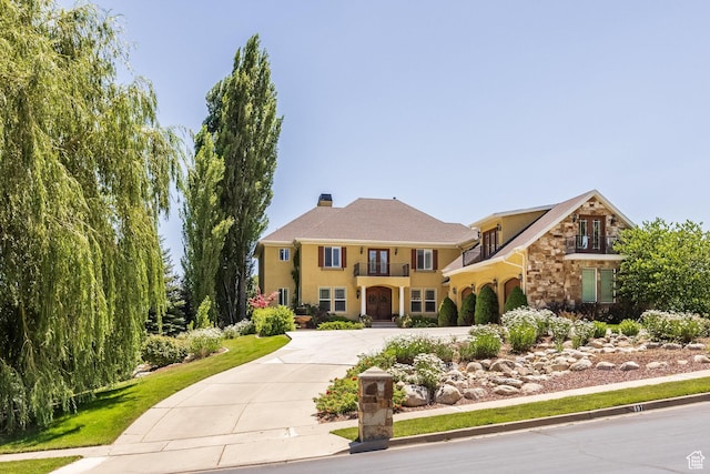 897 W Pfeifferhorn Dr, Alpine, UT 84004 - view of front of property featuring a balcony, curved driveway, stucco siding, stone siding, and a chimney