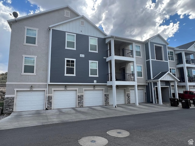 14652 S Astin Ln Unit U102, Herriman, UT 84096 - rear view of house featuring board and batten siding, an attached garage, stone siding, and driveway