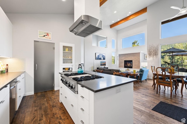 249 S Parkview Dr E, Park City, UT 84098 - kitchen featuring appliances with stainless steel finishes, wall chimney range hood, a towering ceiling, white cabinetry, and a glass covered fireplace