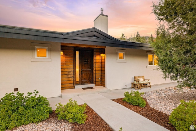 249 S Parkview Dr E, Park City, UT 84098 - exterior entry at dusk featuring a chimney and stucco siding